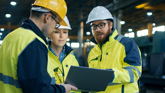 Three construction workers looking at a tablet. 