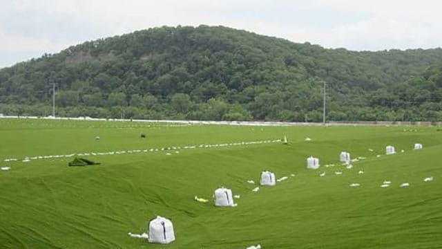 Weighted bags temporarily hold down the turf until sand is swept in, anchoring the turf to the liner below.