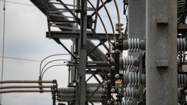 Close-up view of high-voltage equipment, insulators and metal structures at an electrical substation.