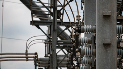 Close-up view of high-voltage equipment, insulators and metal structures at an electrical substation.