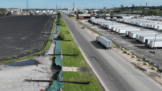 image of storm damage showing power lines and poles on ground along busy roadway