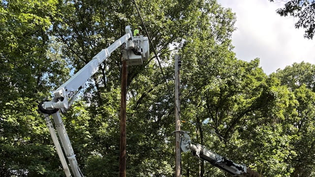 A utility worker in a bucket truck makes power pole repairs.